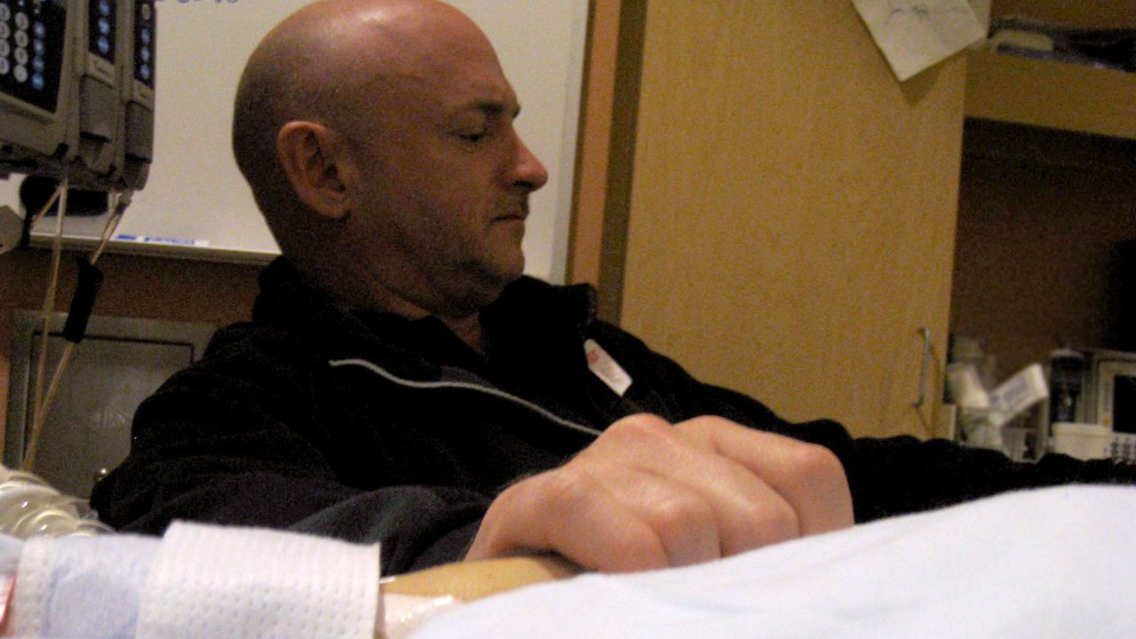 Giffords' husband, Mark Kelly, holds his wife's hand in her hospital room at the University Medical Center in Tuscon on January 9, 2011.