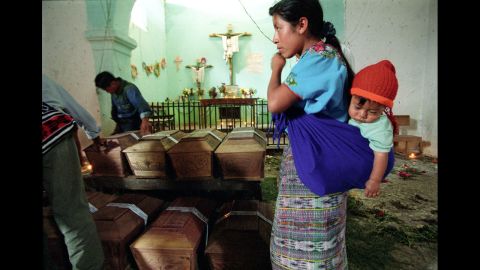 A grieving mother stands over the remains of her daughter at a church in Rabinal, Guatemala, in 2002. Coffins bearing victims' remains were brought to the church months after archaeologists found and exhumed the bodies based on witness testimony. 
