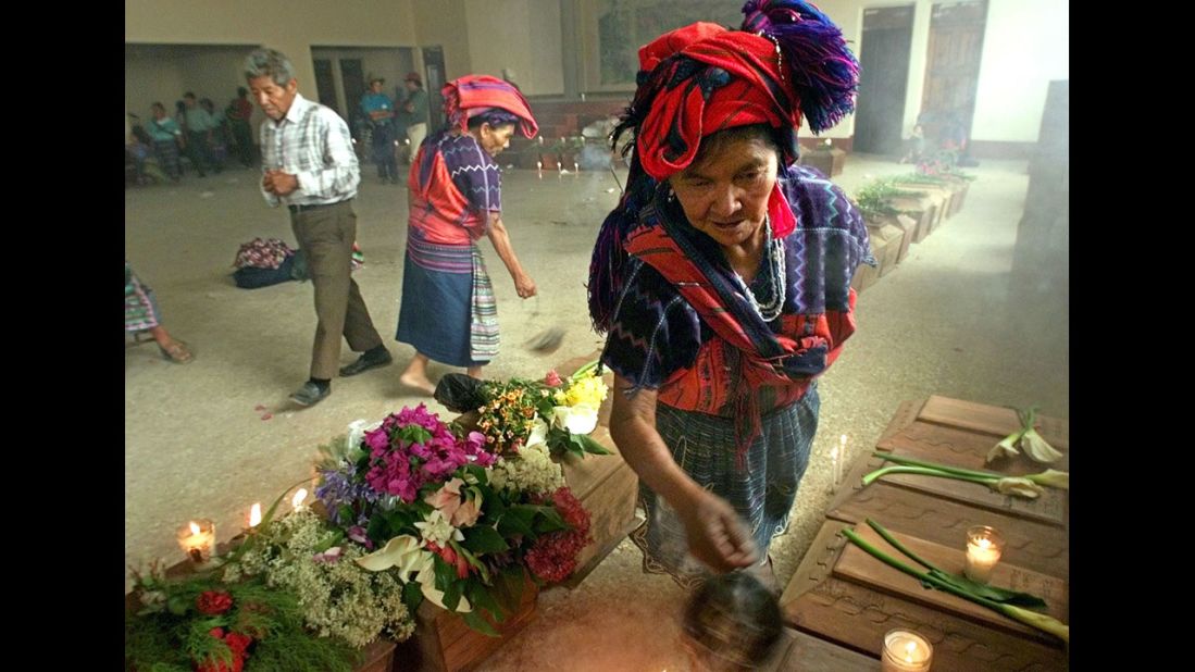 A Mayan woman burns incense over victims' coffins before a funeral in April 2002 in Zacualpa, Guatemala.
