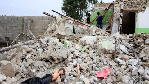 People survey a destroyed house in the village southeast of the Persian Gulf port city of Bushehr.
