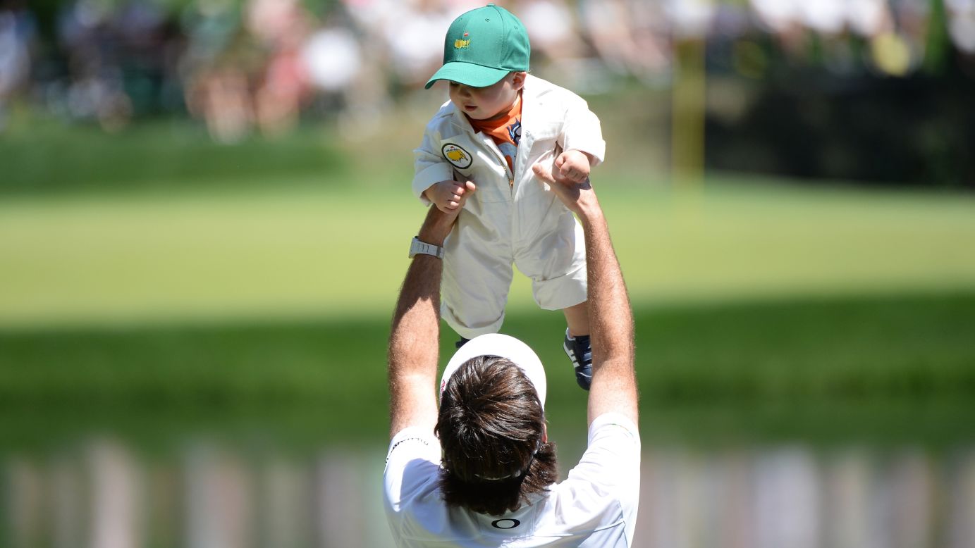 Bubba Watson of the U.S. lifts his son, Caleb, during the Par 3 Contest.