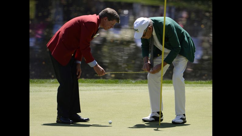 Officials measure how close a ball landed to the pin on the ninth hole during the Par 3 Contest.