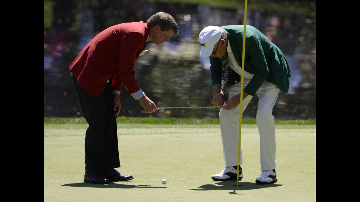 Officials measure how close a ball landed to the pin on the ninth hole during the Par 3 Contest.