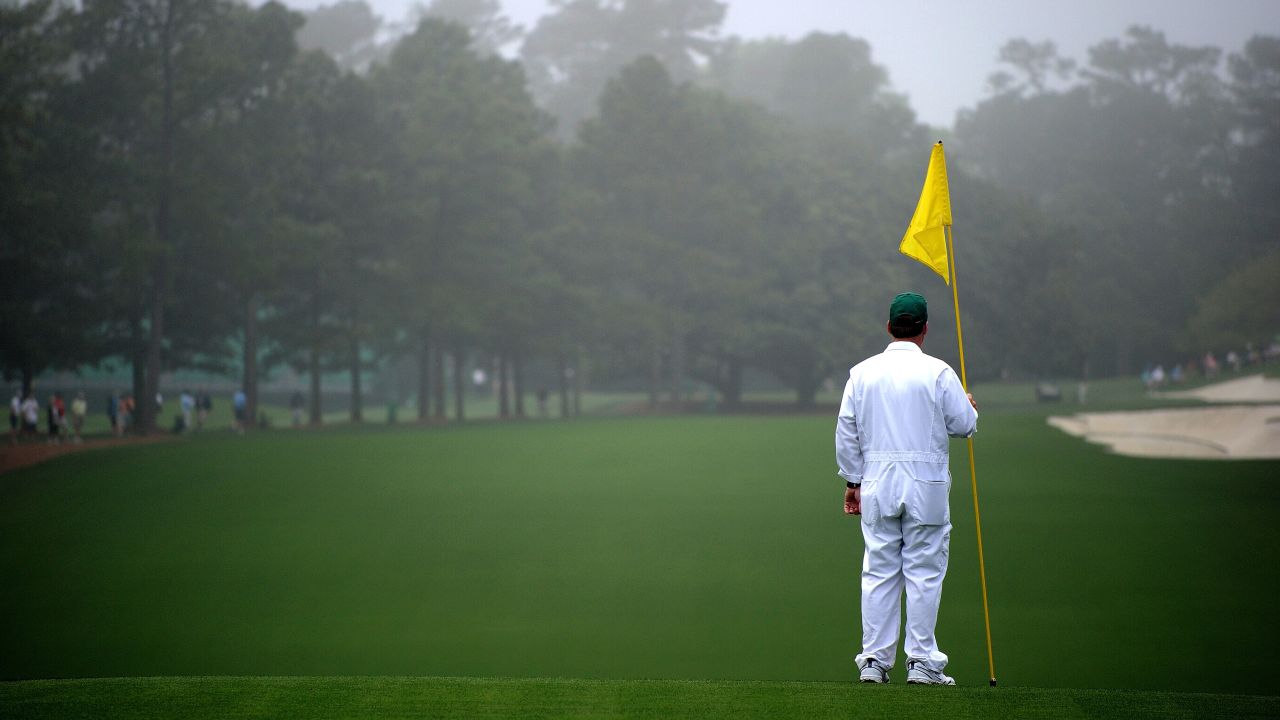 A caddie stands near the first hole before the start of the first round.
