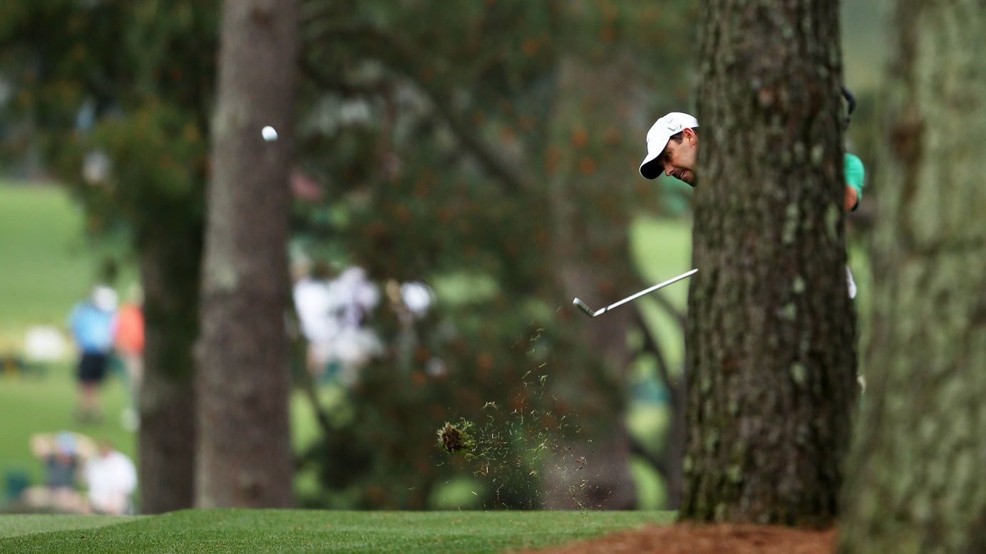 Charl Schwartzel of South Africa hits a shot from behind a tree on the first hole.