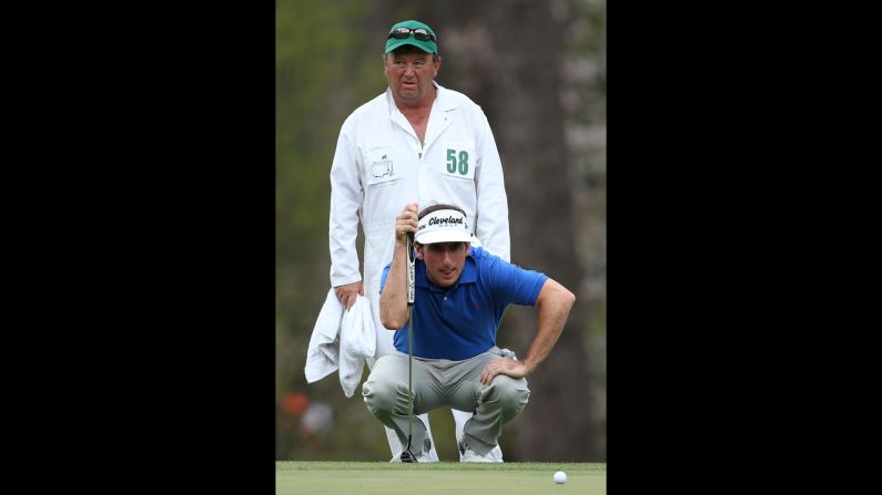 Gonzalo Fernandez-Castano of Spain lines up a putt as his caddie, Jeffrey Paul, looks on from the third green.