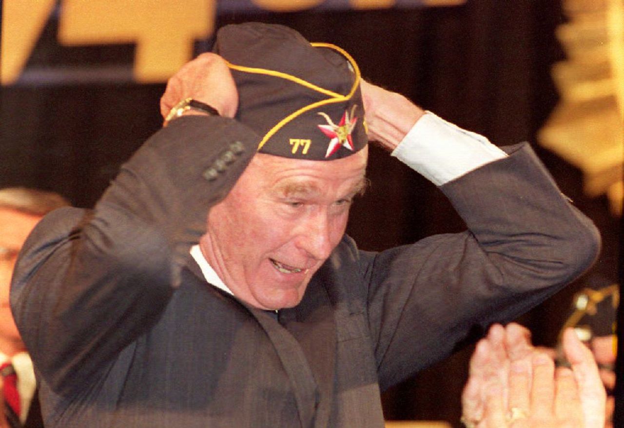 President George Bush tries on a hat given to him by the 74th American Legion at a convention in 1992. 