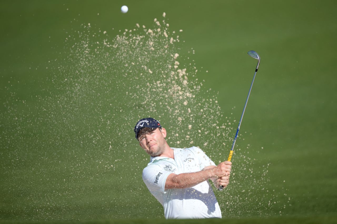 Branden Grace of South Africa hits out of the bunker for eagle on the second hole.