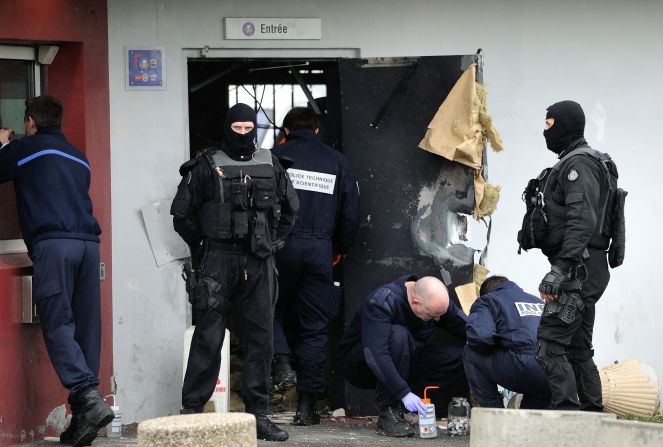 Police officers seek evidence around the destroyed door of the Lille-Sequedin penitentiary on April 13.