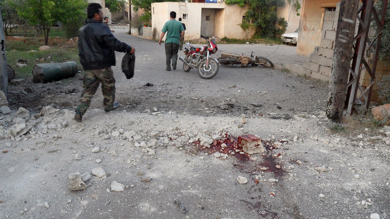 A man walks past bloodstains on a street in the Lebanese border town of Qasr on Sunday, after the shelling.