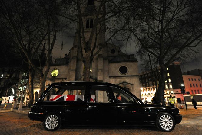 A hearse carrying a coffin waits outside St Clement Danes church.