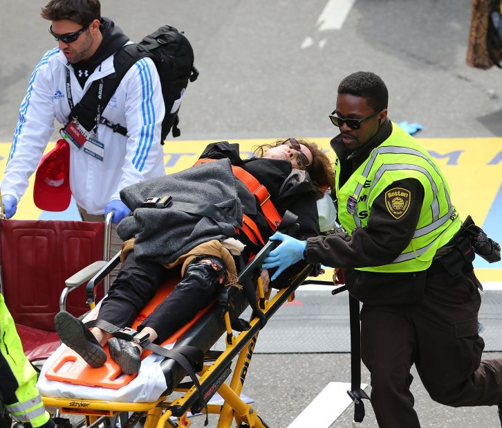 An injured woman is carried away on a stretcher.