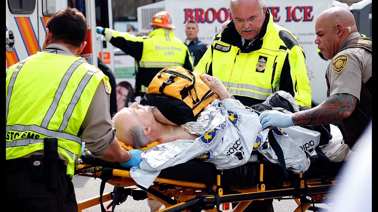 An injured man is prepared to be moved from a stretcher to an ambulance.