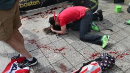 BOSTON - APRIL 15: (EDITOR'S NOTE: THIS IMAGE CONTAINS GRAPHIC CONTENT) A man comforts a victim on the sidewalk at the scene of the first explosion near the finish line of the 117th Boston Marathon. (Photo by John Tlumacki/The Boston Globe via Getty Images)