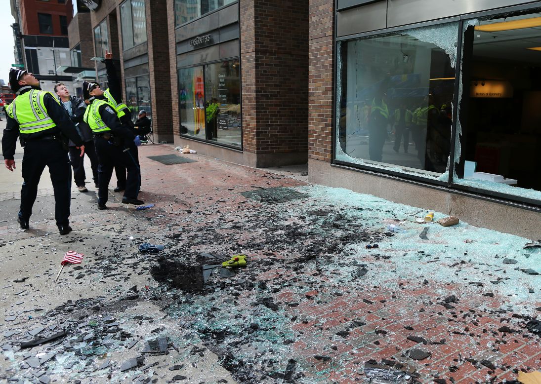 Boston police examine the scene where the first explosion blew out windows on Boylston Street.
