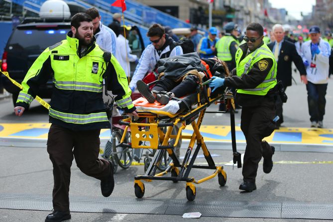 A victim of the explosions is wheeled across the finish line by first responders. 