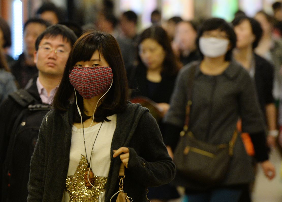 Women wear facemasks as the city's commuters protect themselves against the H7N9 bird flu virus in the downtown area of Shanghai in 2013.