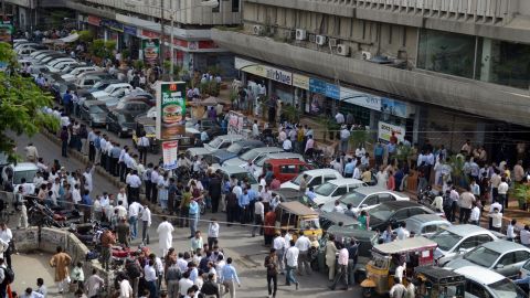 People stand outside after evacuating buildings following tremors in Karachi.