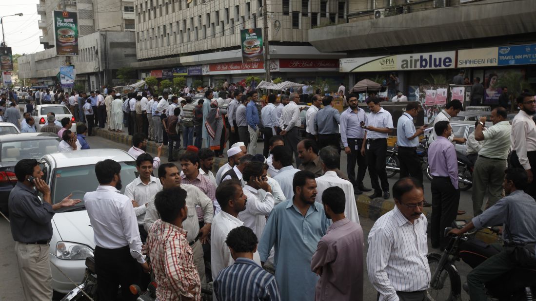 People stand outside their office buildings on Tuesday in Karachi.
