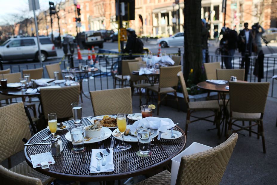 The unfinished meals of fleeing customers are left on tables at an outdoor restaurant in Boston on April 16.