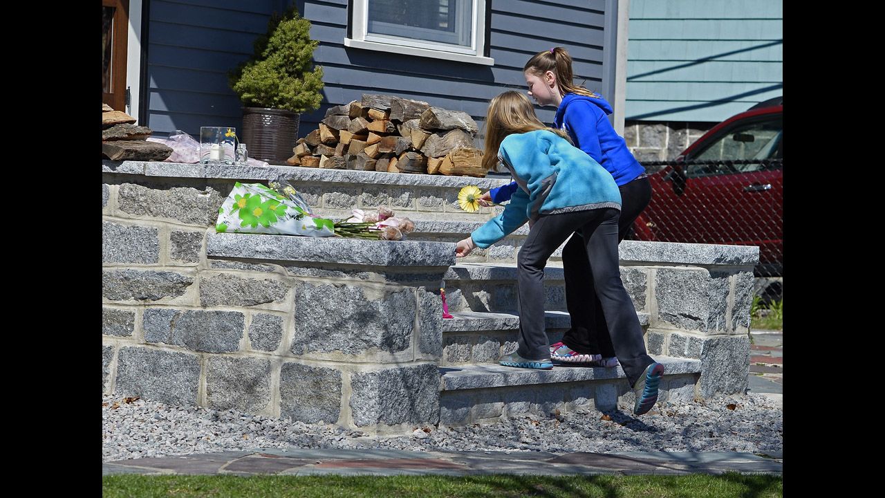 Two young girls leave flowers on the steps outside the Boston home of 8-year-old bombing victim Martin Richard on April 16, 2013.