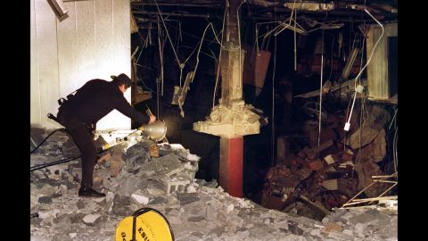 A police photographer helps document the bombing of the underground parking garage at the World Trade Center. That bombing killed six people on February 26, 1993. Six suspects were convicted of participating in the bombing. The seventh suspect, Abdul Rahman Yasin, is still at large. Ramzi Yousef directed the organization and execution of the bombing. He said he did it to avenge the sufferings Palestinian people had endured at the hands of U.S.-aided Israel.