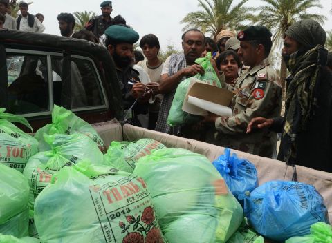 A Pakistani military official distributes relief supplies Wednesday in Mashkell.
