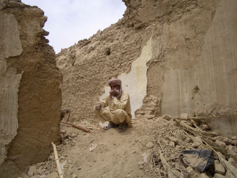 A Pakistani man sits on the remains of his mud house in Mashkell on Wednesday.