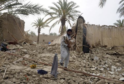 An earthquake survivor carries a goat through the rubble in Mashkell on Wednesday.