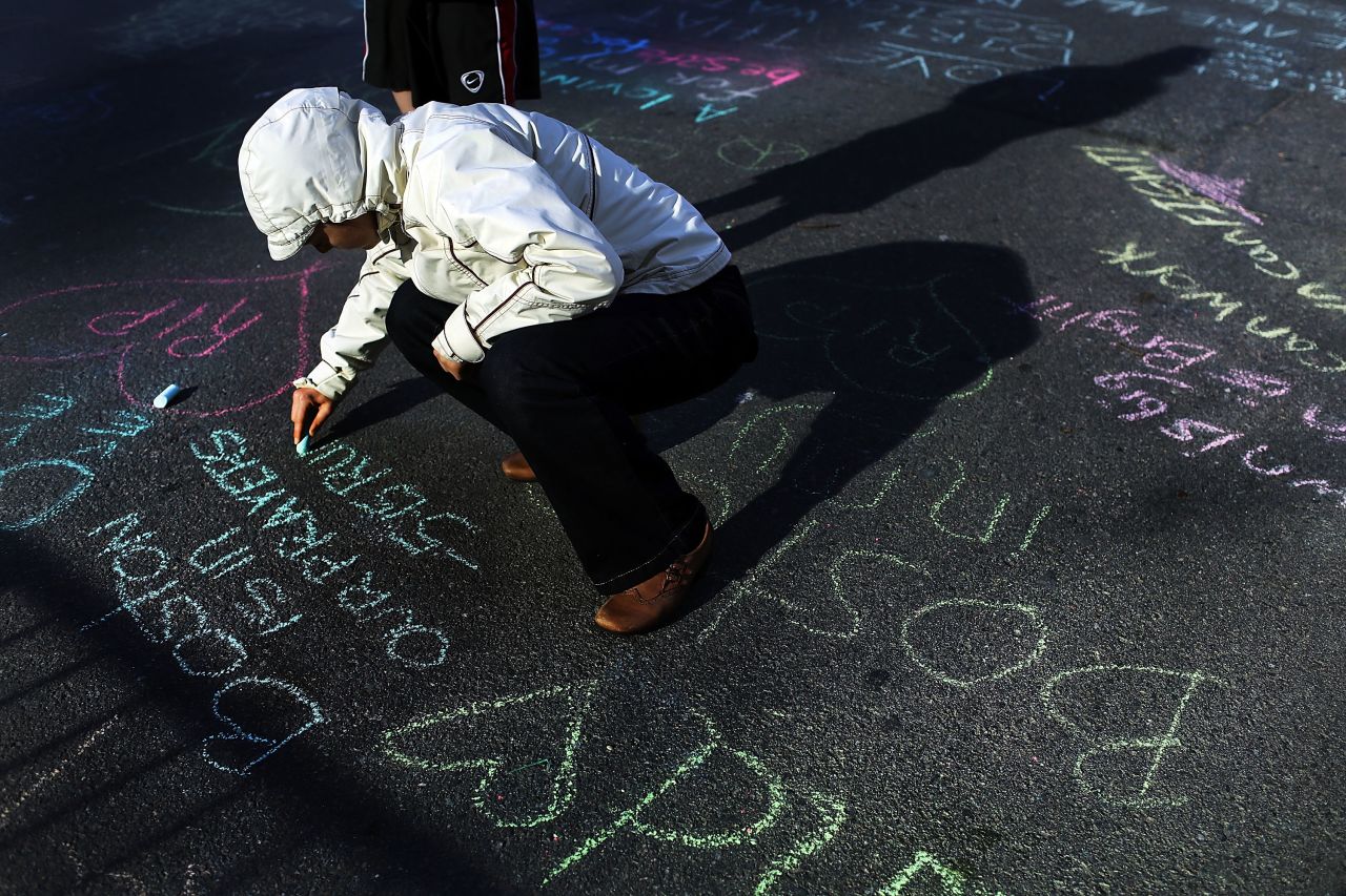 Danielle Cerroni writes a chalk message on the street near the marathon's finish line on April 17, 2013.
