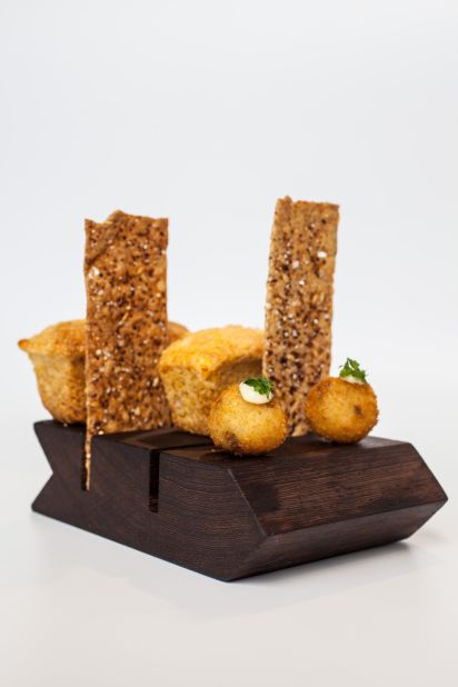Guests at Dovetail's bar are served a complimentary snack trio consisting of a truffle arancini, a whole wheat rosemary cracker and house-made white cheddar cornbread. Dainty and delicious, it's served on a wooden cheese board.