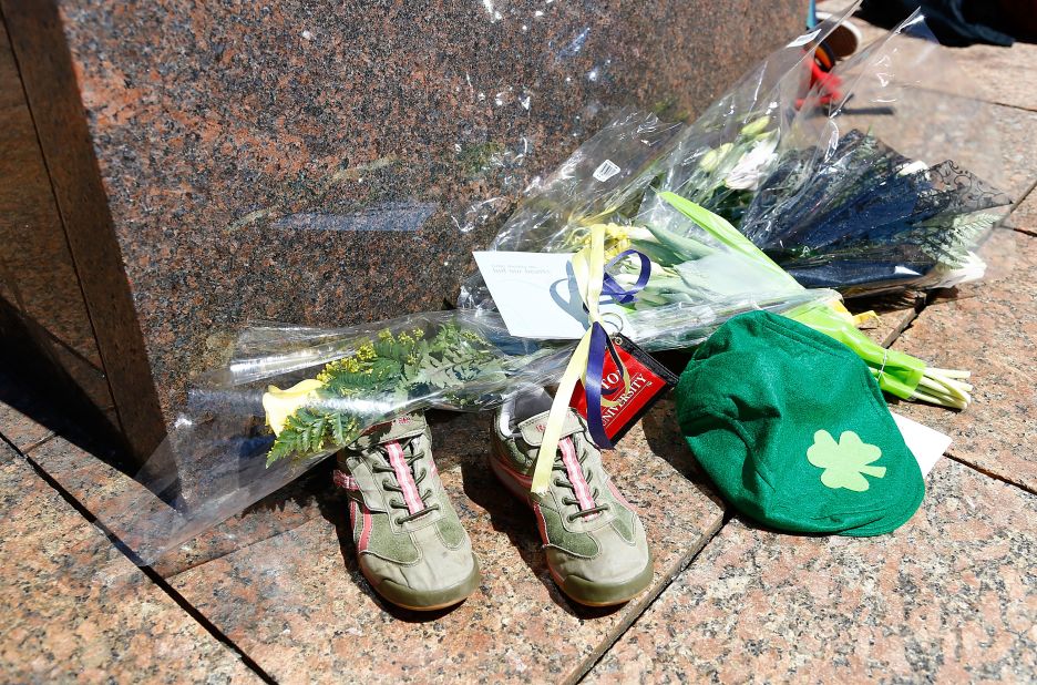 Flowers, running shoes and other items are left in memory of bombing victim Lingzi Lu.