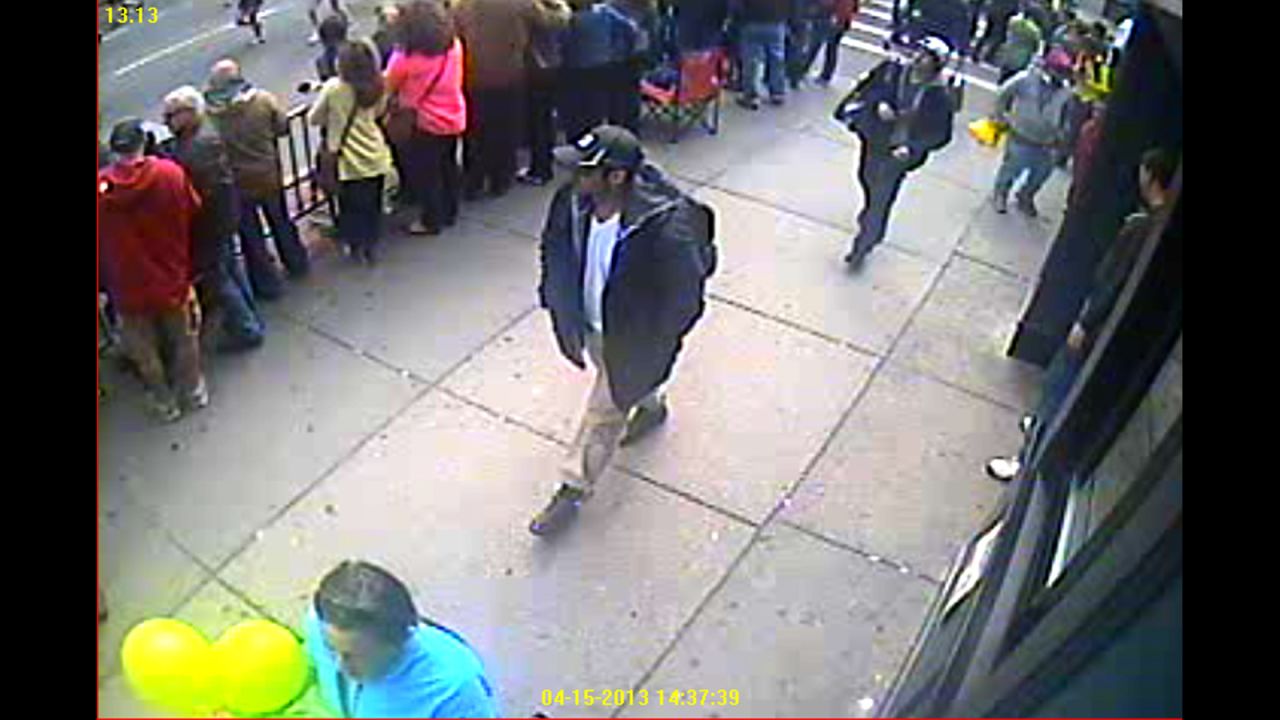 Both suspects are seen walking through the crowd.