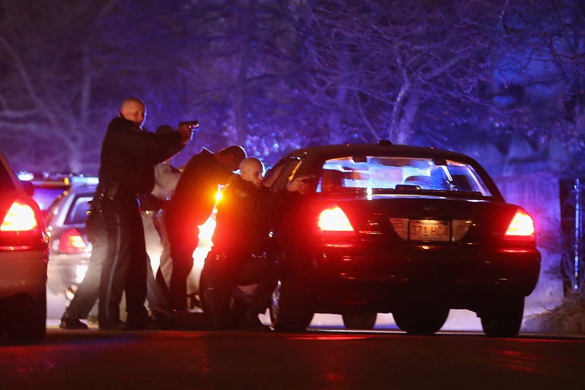 Police with guns drawn search for a suspect on Friday in Watertown, Massachusetts.