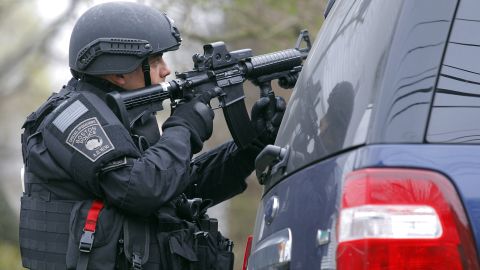 A SWAT team member trains a gun on an apartment building during the search for a suspect in the Boston Marathon bombings.