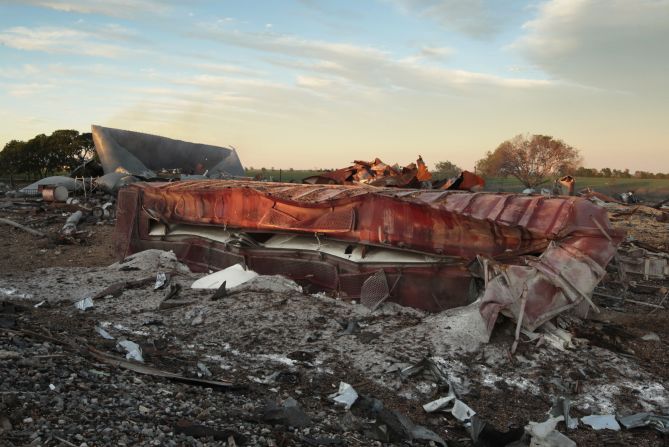 A railroad boxcar lies on its side near the plant.