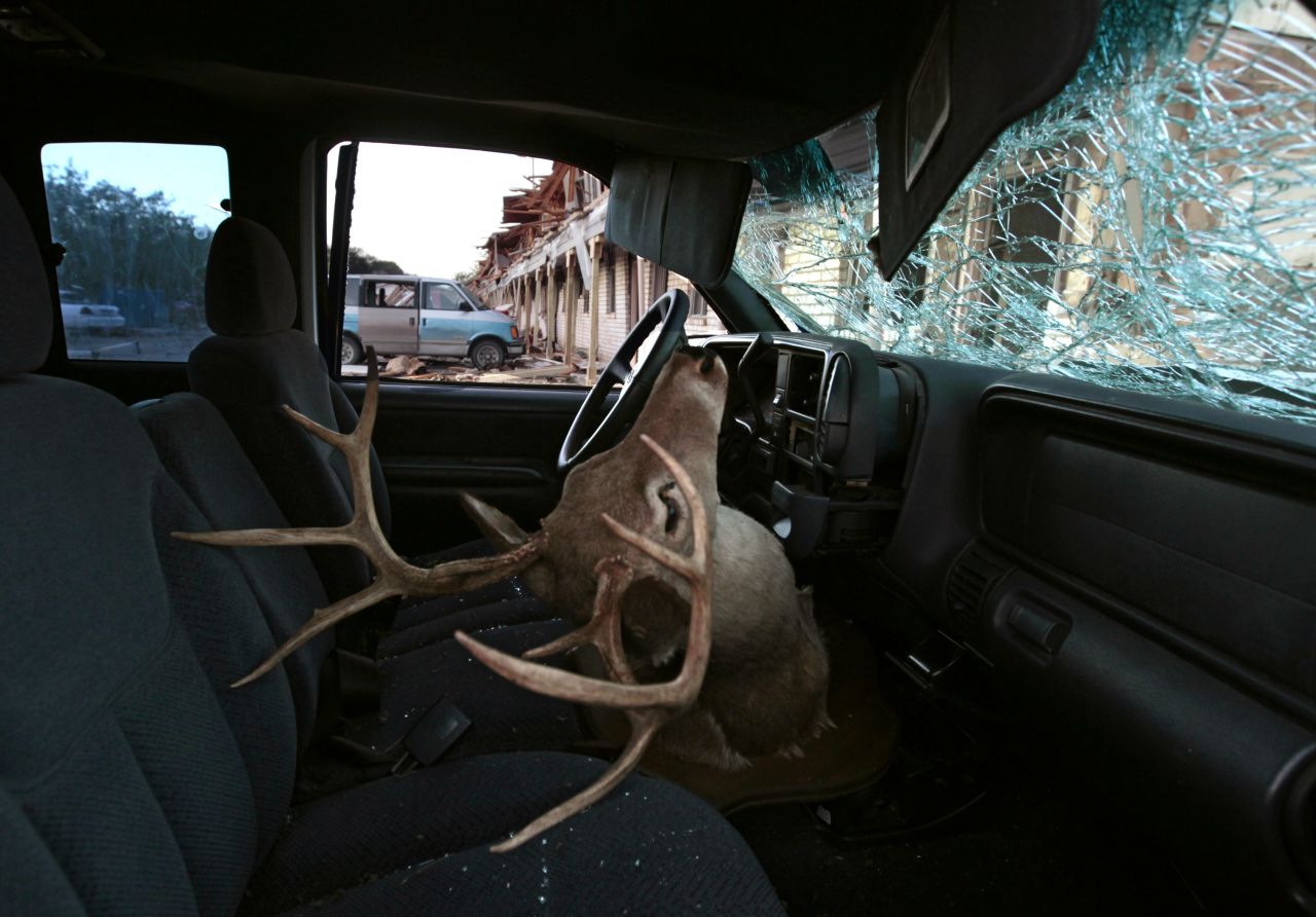 A deer head mount sits inside a car parked next to an apartment complex damaged in the explosion.