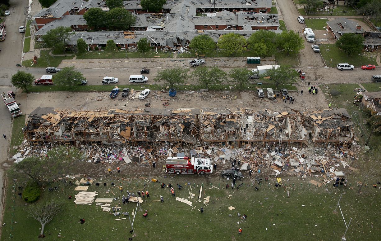Search and rescue workers comb through what remains of a 50-unit apartment building, in foreground, and a nursing home on April 18, 2013.
