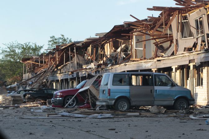 The remains of an apartment complex lie on cars.