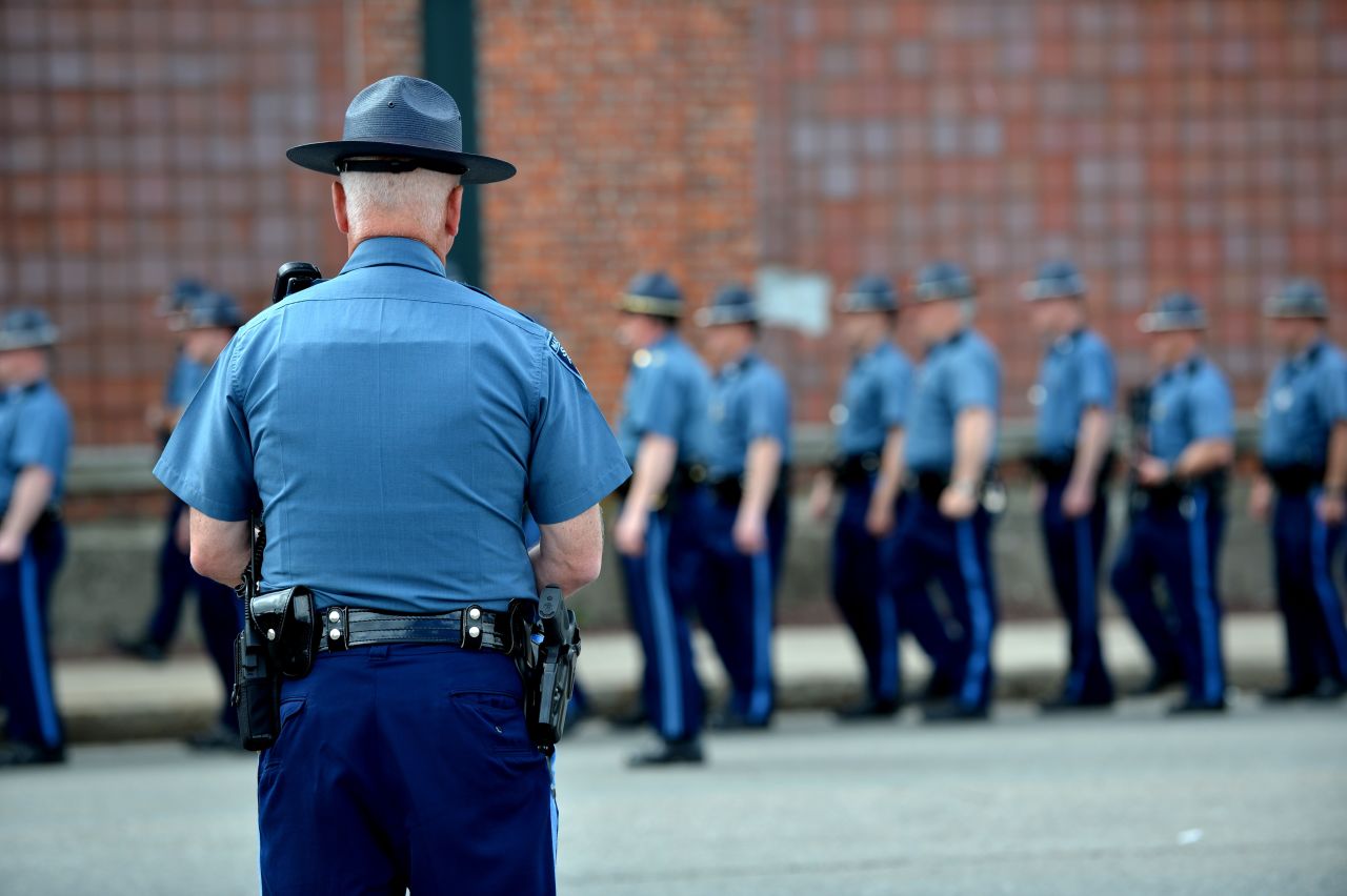 A Massachusetts state trooper watches other troopers line up at Watertown Mall as the manhunt for the second suspect continues in Watertown on Friday.