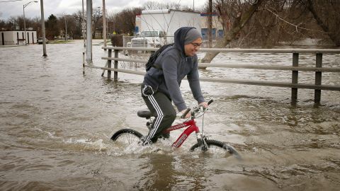 Hector Duran uses his bike to get through floodwater on Friday, April 19, in Des Plaines, Illinois. The suburban Chicago town is battling rising floodwater from the Des Plaines River.