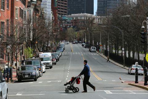 A man crosses a vacant Beacon Street, across from Boston Common.