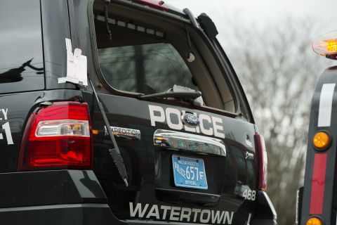 A Watertown police vehicle with bullet holes in its body and a shattered windshield is towed out of the search area on April 19 in Watertown, Massachusetts.
