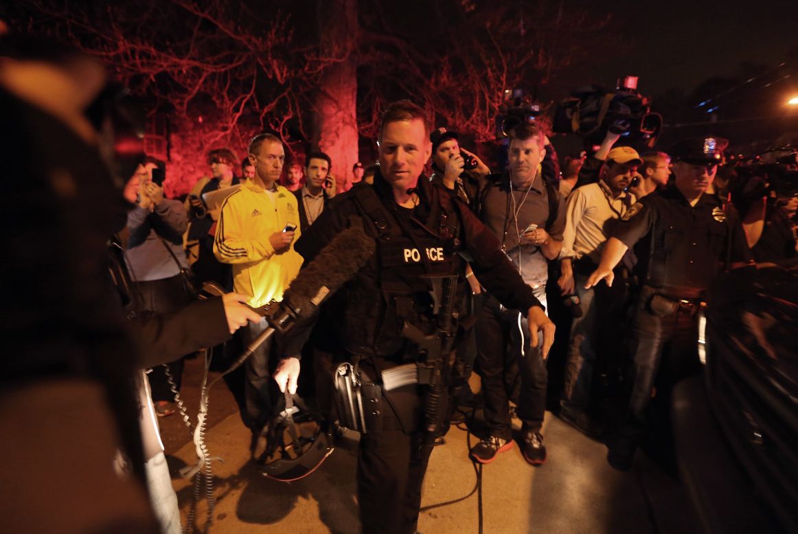 A SWAT team member is followed by reporters and a celebrating crowd  on April 19 after the successful operation.