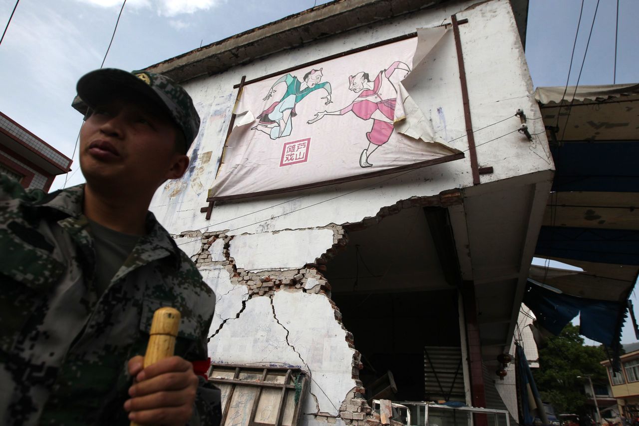 A rescuer stands by a damaged building in Longmen on Saturday.