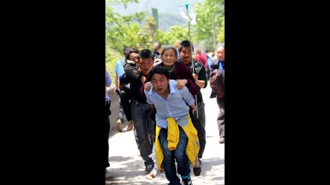 Residents help carry injured people to the hospital on Saturday in the city of Ya'an.