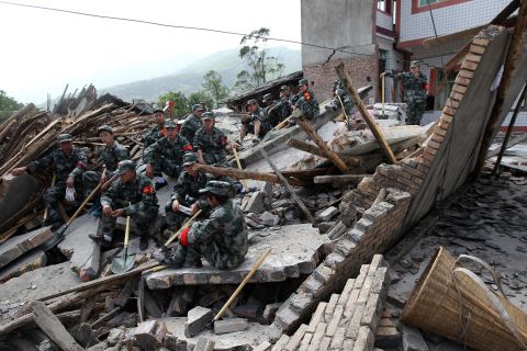 Rescuers sit on ruins of a house in Longmen, an area close to the epicenter of the earthquake.