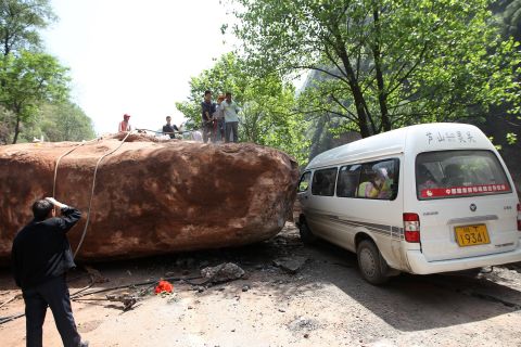 People attempt to move a huge rock blocking the road to Longmen township on Saturday.