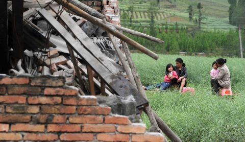 Residents rest near destroyed houses in Sichuan Province on Saturday.