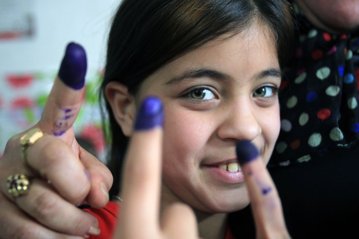 An Iraqi girl is surrounded by the ink-stained fingers of women after they voted on Saturday.